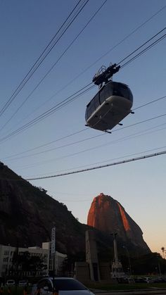 a cable car going up the side of a mountain with power lines in front of it