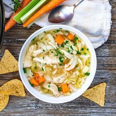 a bowl of chicken noodle soup with carrots, celery and tortilla chips