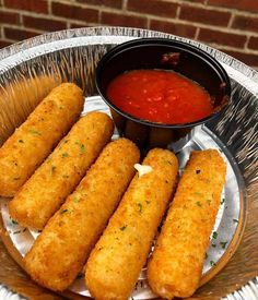 some fried food is on a silver plate with sauce in a bowl next to it