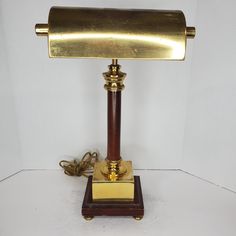 an antique brass and wood desk lamp on a wooden base with a cord plugged into it