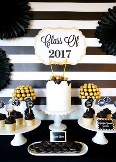 a table topped with cakes and cupcakes on top of white pedestals next to black and white striped wall