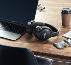 an open laptop computer sitting on top of a wooden desk next to headphones and a cell phone