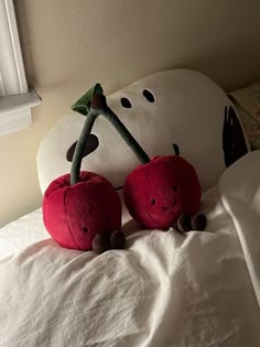 two stuffed apples sitting on top of a bed next to a snowman head and nose