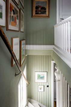 the stairs are lined with framed pictures and artwork on the wall above them is a bench