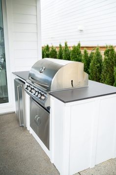 an outdoor kitchen with stainless steel appliances and grilling area in front of the house