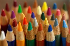 many colored pencils are lined up in a close up shot, with the rest of the rainbow colored pencils visible