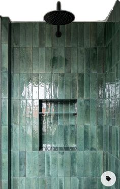 a green tiled bathroom with a shower head