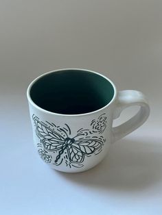 a black and white coffee cup sitting on top of a table