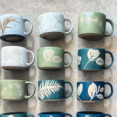 there are many coffee cups that have been painted with leaves and flowers on them, all in different colors