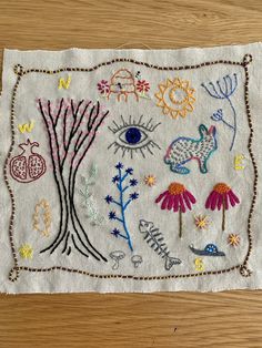 a piece of cloth with embroidered designs on it sitting on top of a wooden table