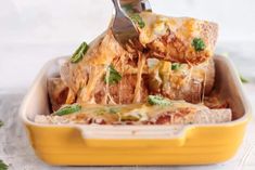 a person is taking a slice of pizza out of a casserole dish with a fork