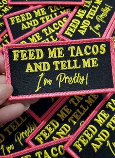 someone is holding up some patches that say feed me tacos and tell me i'm pretty