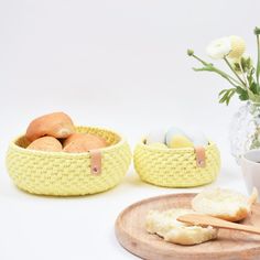 some bread and eggs are on a wooden plate next to a vase with flowers in it