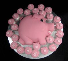 there is a cake that looks like a pig on top of some cupcakes