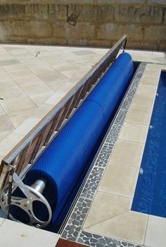 an empty swimming pool in the middle of a patio with a blue cover over it