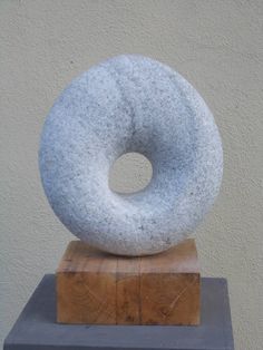 a large white doughnut sitting on top of a wooden block in front of a wall