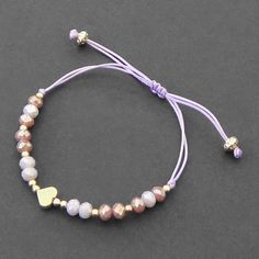 a bracelet with beads and a heart charm on it, sitting on a gray surface