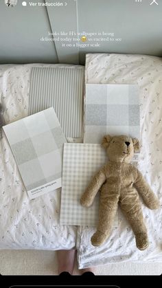 a teddy bear laying on top of a bed next to pillows