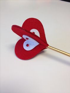 a red heart shaped object with a gold arrow sticking out of it