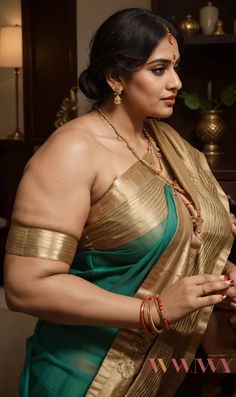 a woman in a green and gold saree is looking down at something on the table