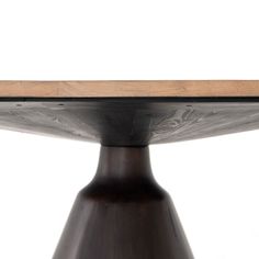 a close up of a wooden table top on a metal base with a white wall in the background