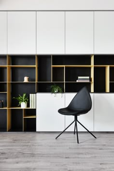 a black chair sitting in front of a bookshelf