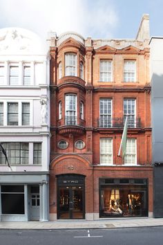 an old brick building on the corner of a street in front of two tall buildings