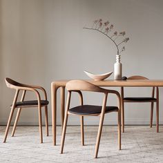 two chairs and a table with a vase on it in front of a white wall