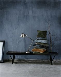 a room with blue walls and a black coffee table topped with a pile of pillows