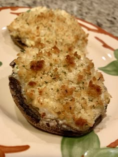 an eggplant and cheese stuffed mushroom is on a floral plate with green leaves