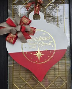 a christmas ornament hanging on the side of a door with red and white ribbon