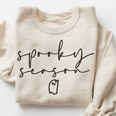 a white sweatshirt with the words spooky season written on it in black ink