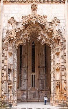 two people are standing in front of an ornate building with stone columns and carvings on the walls