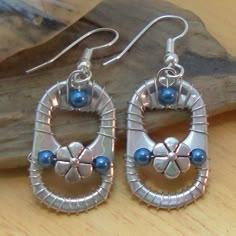 two pairs of silver and blue beaded earrings sitting on top of a wooden table