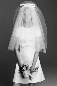 black and white photograph of a woman wearing a wedding dress with a veil over her head