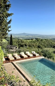 an outdoor swimming pool with lounge chairs overlooking the countryside