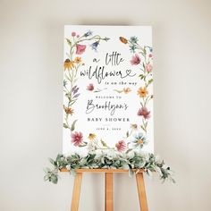 a sign with flowers on it sitting next to a easel