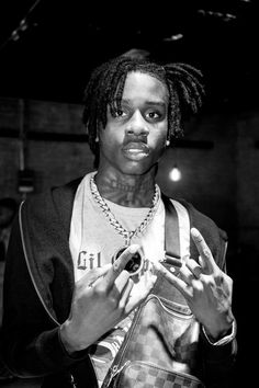 a young man with dreadlocks is looking at his cell phone while standing in a dark room