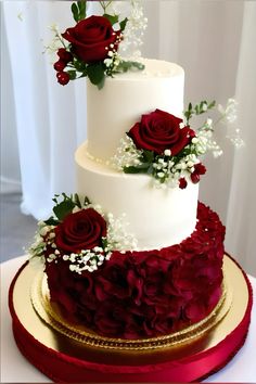 a three tiered wedding cake with red roses on top