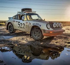 an old race car is parked in the mud