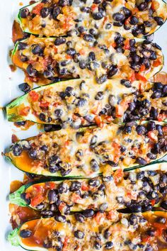 stuffed zucchini boats filled with black olives and cheese on a white plate