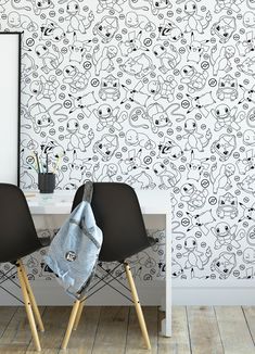 two black chairs sitting in front of a white wall with cartoon faces on the wall