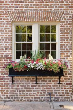 a window box filled with flowers next to a brick building