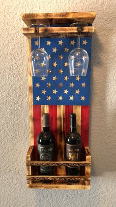 two wine glasses sitting on top of a wooden shelf with an american flag painted on it