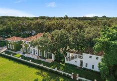 an aerial view of a large white house surrounded by trees