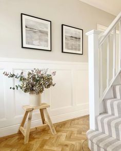 a vase with flowers sitting on top of a wooden table next to a stair case