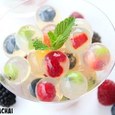 a bowl filled with fruit and ice cream on top of a white table next to berries