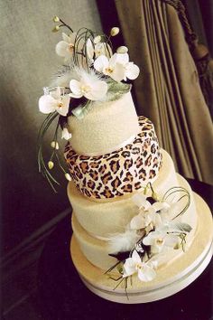 a three tiered cake with white flowers and leopard print