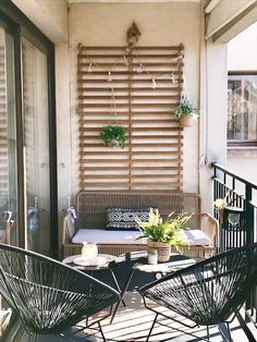 two chairs and a table on a balcony with plants hanging from the wall behind them