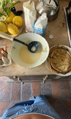 a table topped with lots of food next to a bowl filled with eggs and pancakes